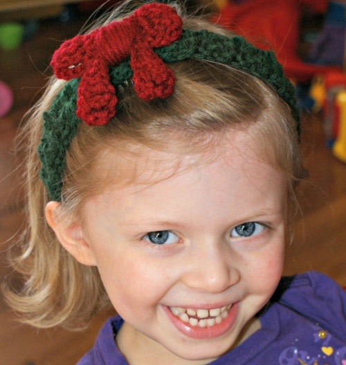 Holiday Wreath Headband - This list of unique crochet baby headbands for girls are sweet and simple. You can whip these free crochet patterns up in no time, and there are so many options. #CrochetBabyHeadbands #BabyHeadbandPatterns #FreeCrochetPattern