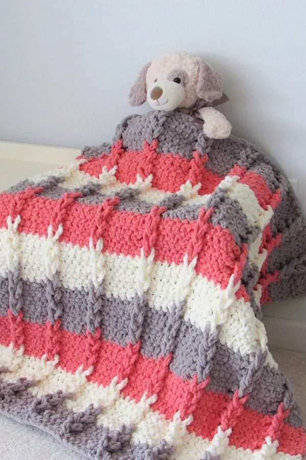 a stuffed toy covered with a braided crochet blanket