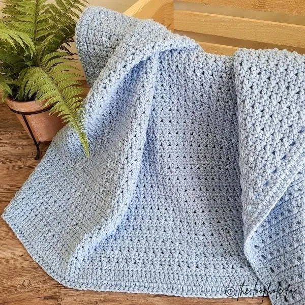 the crossed double crochet blanket beside a plant