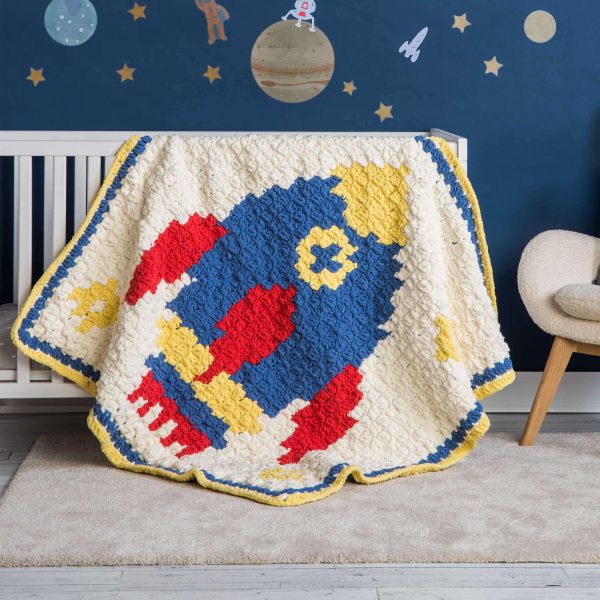 A cute crochet baby blanket on the side of a crib