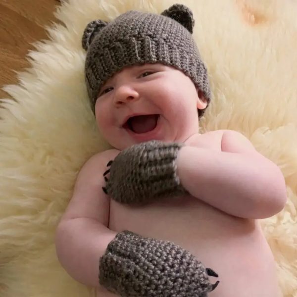 a baby wearing a crochet bear hat and mittens