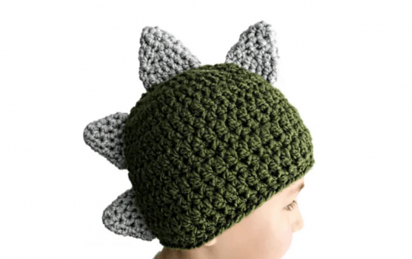 a child wearing a dinosaur crochet hat