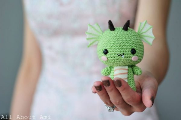woman holding mini crochet dragon