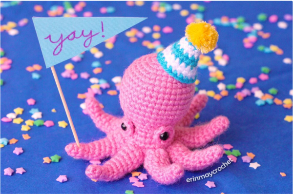 crochet amigurumi party octopus holding a stick with yay sign